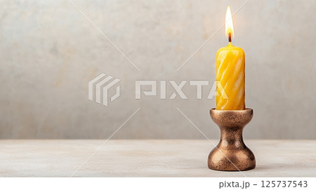 Beeswax Candle Burning Brightly In A Textured Copper Candlestick On Cream Surface 125737543