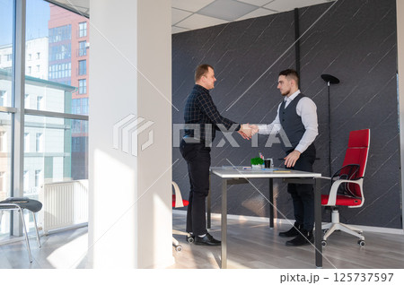 Two Caucasian men shaking hands. Interview or business meeting. Two Caucasian men shaking hands. Interview or business meeting. 125737597