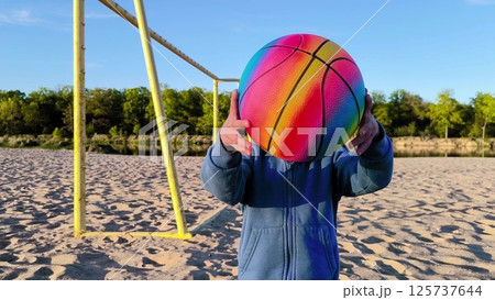 Close-up. A happy little boy is playing with a colorful ball in nature. Happy Family Of Children Having Fun In Spring Park. little boy playing with ball Close-up. A happy little boy is playing with a colorful ball in nature. Happy Family Of Children Having Fun In Spring Park. little boy playing with ball 125737644