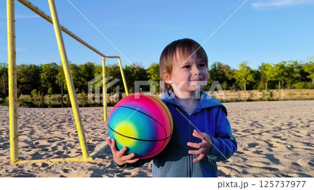 Close-up. A happy little boy is playing with a colorful ball in nature. Happy Family Of Children Having Fun In Spring Park. little boy playing with ball Close-up. A happy little boy is playing with a colorful ball in nature. Happy Family Of Children Having Fun In Spring Park. little boy playing with ball 125737977