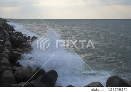 風の強い海岸でテトラポッドに激突する力強い波 125739372