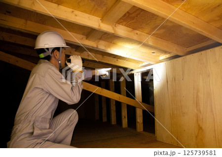 住宅の屋根裏で業務にあたる業者 住宅の屋根裏で業務にあたる業者 125739581