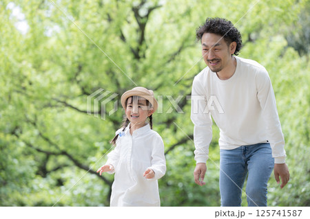 緑の背景で公園で娘と遊ぶ父親と娘の親子の幸せや未来、幸福、見守るや子育てなどのイメージ 125741587