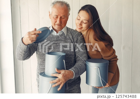 Grandfather at home. Old man with granddaughter. Senior in a gray sweater. Family with presents. Grandfather at home. Old man with granddaughter. Senior in a gray sweater. Family with presents. 125743488