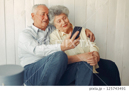Grandparents at home. Old people use a phone. Senior in a blue shirt. Grandparents at home. Old people use a phone. Senior in a blue shirt. 125743491