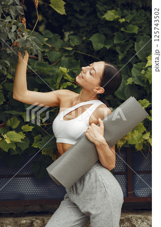 Pretty lady in a park. Brunette prepare to yoga. Girl in a sportsuit. 125743502