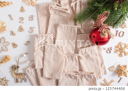 Christmas advent calendar with gift velvet bags and wooden numbers on a white background. Eco-friendly 125744408