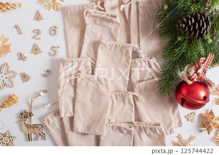 Christmas advent calendar with gift velvet bags and wooden numbers on a white background. Eco-friendly 125744422