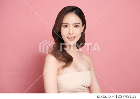 A beautiful young Asian woman with clean, fresh skin against a pink background. Skincare, facial treatment, cosmetology, beauty, and spa. An elegant portrait of an Asian woman. A beautiful young Asian woman with clean, fresh skin against a pink background. Skincare, facial treatment, cosmetology, beauty, and spa. An elegant portrait of an Asian woman. 125745118