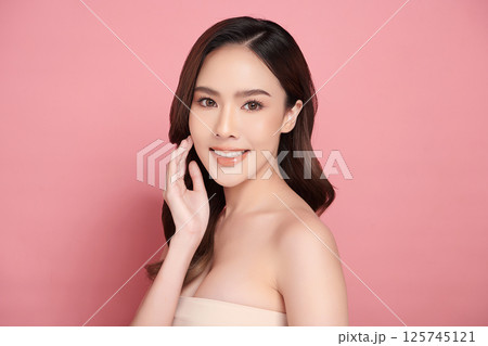 A beautiful young Asian woman with clean, fresh skin against a pink background. Skincare, facial treatment, cosmetology, beauty, and spa. An elegant portrait of an Asian woman. A beautiful young Asian woman with clean, fresh skin against a pink background. Skincare, facial treatment, cosmetology, beauty, and spa. An elegant portrait of an Asian woman. 125745121