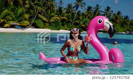Tourist enjoying a cocktail on a giant inflatable flamingo Tourist enjoying a cocktail on a giant inflatable flamingo 125745708