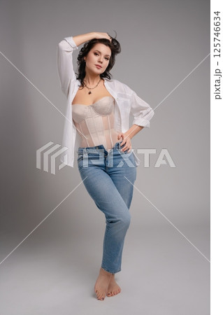 Elegant beauty poses in a corset and casual jeans for a fashion shoot 125746634