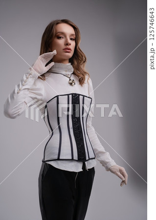 Elegant woman in corset and gloves showcases modern fashion style Elegant woman in corset and gloves showcases modern fashion style 125746643