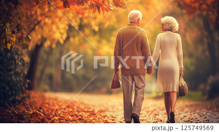 Elderly couple walking in autumn park holding hands 125749569