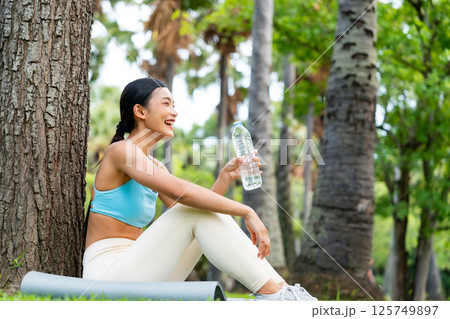 Young Asian woman in activewear sitting under a tree 125749897