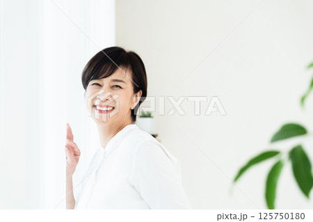 窓辺に立つシニア女性 窓辺に立つシニア女性 125750180