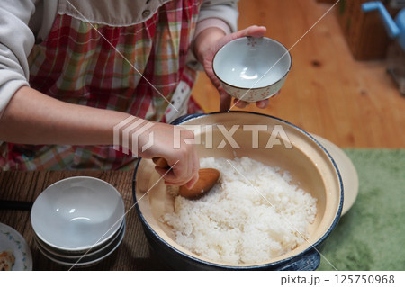 土鍋で炊いたご飯をよそう女性 125750968