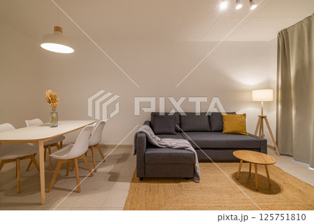 Living room view with grey sectional sofa and round coffee table next to the dining area in a cozy apartment 125751810