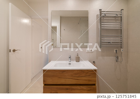 Modern bathroom with wood vanity, large wall mirror, chrome towel warmer and glass shower area Modern bathroom with wood vanity, large wall mirror, chrome towel warmer and glass shower area 125751845