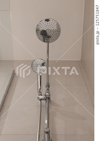 Low angle view of chrome shower fixture with large rain shower head and handheld shower attachment Low angle view of chrome shower fixture with large rain shower head and handheld shower attachment 125751847