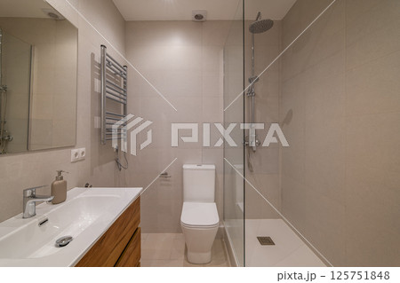 Bathroom with wood vanity, wall-mounted mirror, chrome towel warmer and glass shower enclosure Bathroom with wood vanity, wall-mounted mirror, chrome towel warmer and glass shower enclosure 125751848