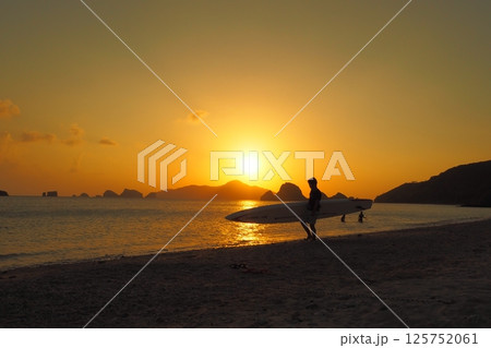 夕日の沈む浜辺を歩く人　沖縄の夕景 125752061