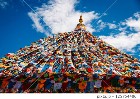 The Changqing Chunker Temple  in Litang, China. Many colourful prayer flags on the mountain top beside the temple.Spirituality and meditation. 125754486