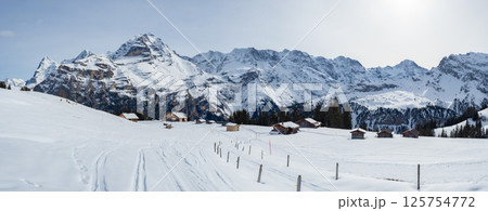 Muerren, Switzerland - February 21st 2024: Beautiful huts in the skiing resort in front of Jungfrau peak Muerren, Switzerland - February 21st 2024: Beautiful huts in the skiing resort in front of Jungfrau peak 125754772