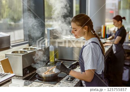 A talented chef is preparing a gourmet dish in a beautifully designed modern kitchen setting 125755857