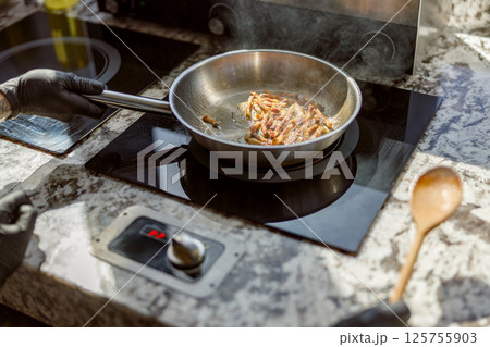 Sizzling bacon is cooking in a modern kitchen, filling the air with delightful aromas 125755903