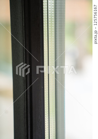 Textured aluminum frame with visible glazing spacer and forest background 125756167