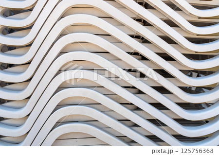 Stacked white sun loungers with curved lines, abstract summer pattern Stacked white sun loungers with curved lines, abstract summer pattern 125756368