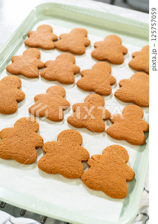A top-down view of a baking tray filled with Orange Zest Gingerbread Cookies cooling after baking, emphasizing their neat arrangement. A top-down view of a baking tray filled with Orange Zest Gingerbread Cookies cooling after baking, emphasizing their neat arrangement. 125757059