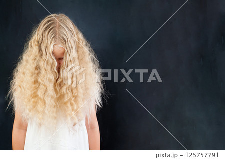 Blond girl with long wavy healthy hair on black background 125757791