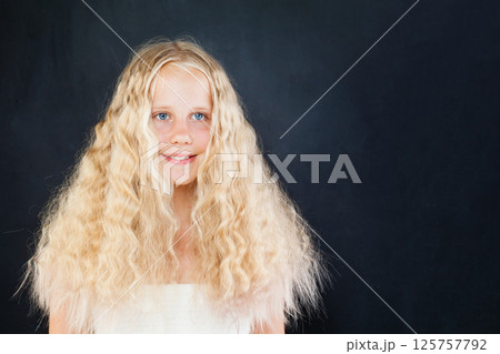Happy child with blond long wavy hair posing on black background, fashion portrait Happy child with blond long wavy hair posing on black background, fashion portrait 125757792