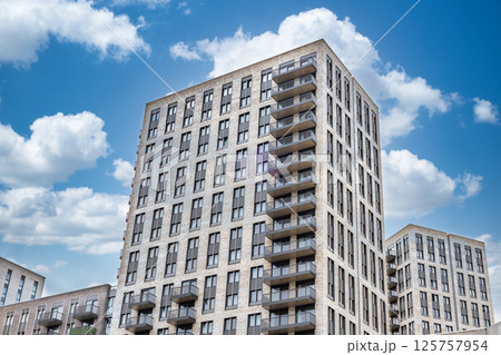 Modern apartment building with balconies and glass windows under blue sky 125757954