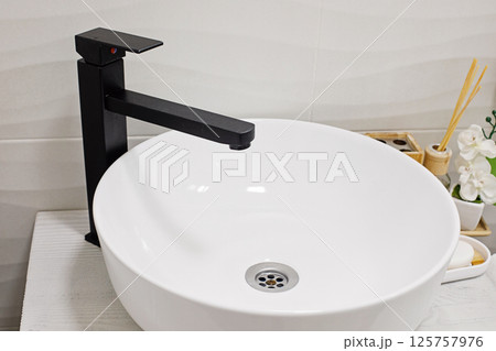 White sink and black faucet in modern Scandi bathroom, interior detail 125757976