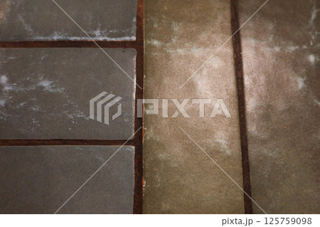 close-up of two different types of floor tiles. On the left, there are square tiles in a muted gray color with subtle mottled patterns. On the right, there is a long, rectangular tile in a light brown close-up of two different types of floor tiles. On the left, there are square tiles in a muted gray color with subtle mottled patterns. On the right, there is a long, rectangular tile in a light brown 125759098