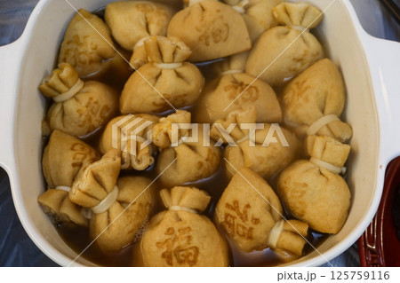 close up of a big pot of boiled Japanese tofu (bean curd) pouches with rice cake (mochi kinchaku) with a Japanese word "Luck" on it close up of a big pot of boiled Japanese tofu (bean curd) pouches with rice cake (mochi kinchaku) with a Japanese word "Luck" on it 125759116