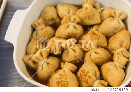 close up of a big pot of boiled Japanese tofu (bean curd) pouches with rice cake (mochi kinchaku) with a Japanese word "Luck" on it close up of a big pot of boiled Japanese tofu (bean curd) pouches with rice cake (mochi kinchaku) with a Japanese word "Luck" on it 125759120