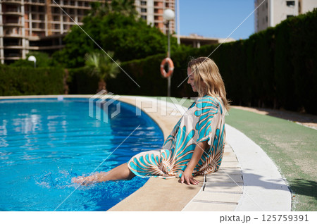 Woman Relaxing by a Swimming Pool on a Bright Sunny Day 125759391