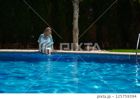 Woman Relaxing by a Serene Pool on a Sunny Day Outdoors 125759394