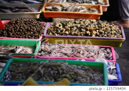 Fresh fish of various types displayed in blue plastic trays, likely at a market or fishmongers stall, ready for sale or cooking. 125759404