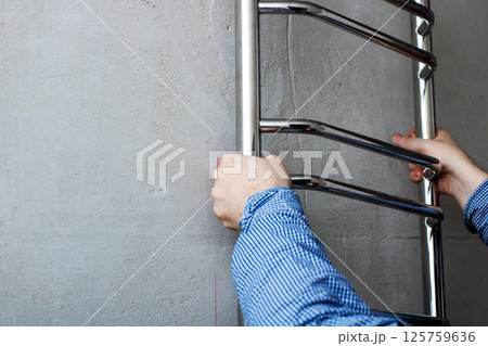 A person is carefully installing a towel rack onto a wall surface A person is carefully installing a towel rack onto a wall surface 125759636