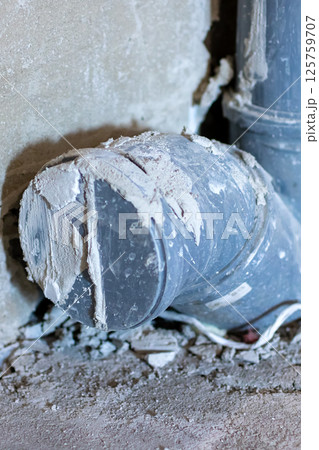 A broken pipe is lying on the ground right next to a wall nearby A broken pipe is lying on the ground right next to a wall nearby 125759707