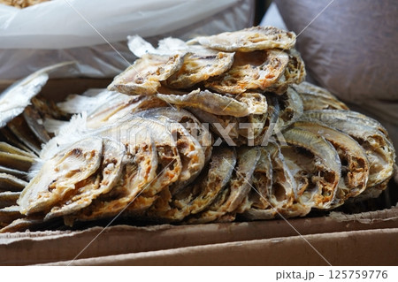 Dried fish neatly stacked in a cardboard box, showcasing preserved seafood ready for sale or storage. 125759776