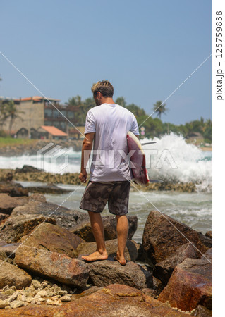 Surfer Walking on Rocks Along the Beach, Embracing the Spirit of Adventure and Freedom 125759838