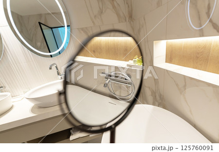 A modern bathroom interior with illuminated round mirrors and elegant design reflections A modern bathroom interior with illuminated round mirrors and elegant design reflections 125760091