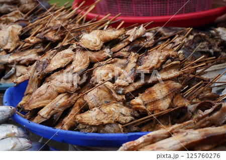 Smoked fish piled in a basket, ready for sale at a market, showcasing a popular street food or local delicacy. 125760276