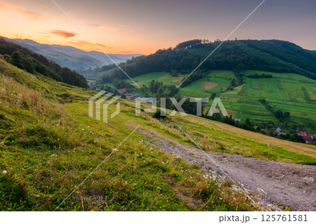 rural landscape in summer. fresh morning. village in the valley at dawn. forest and green meadow on the hill under red sky. scenic view of a countryside in mountains of ukraine rural landscape in summer. fresh morning. village in the valley at dawn. forest and green meadow on the hill under red sky. scenic view of a countryside in mountains of ukraine 125761581
